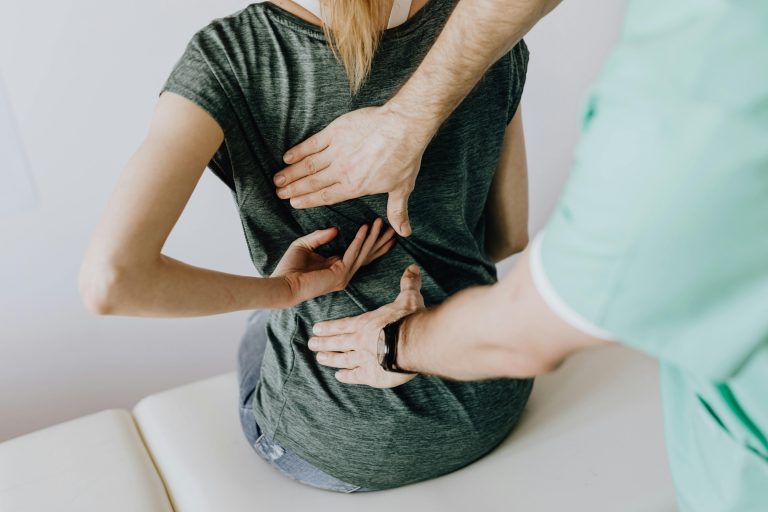Doctor examining a patient’s back for pain management and spinal assessment.